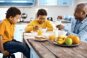 two sons and father eating breakfast